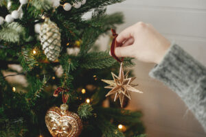 Hands decorating christmas tree with stylish vintage bauble in festive room. Merry Christmas!